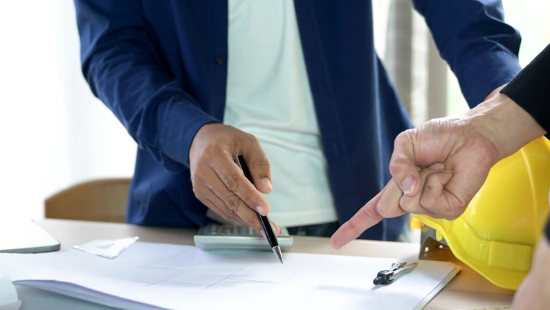 Two hands of men on holding a pen pointing at the design on the table